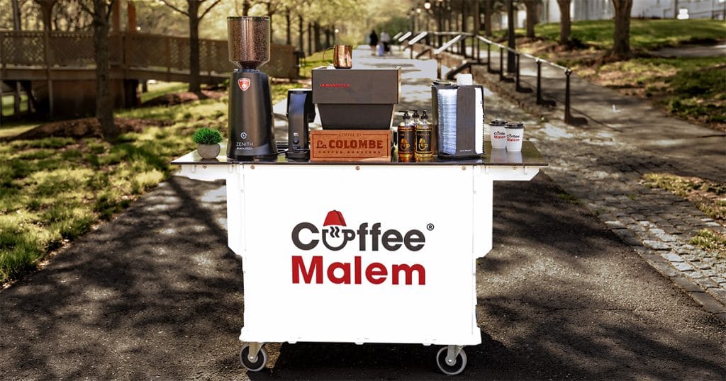 Coffee Malem mobile coffee cart with espresso equipment on a tree-lined path.