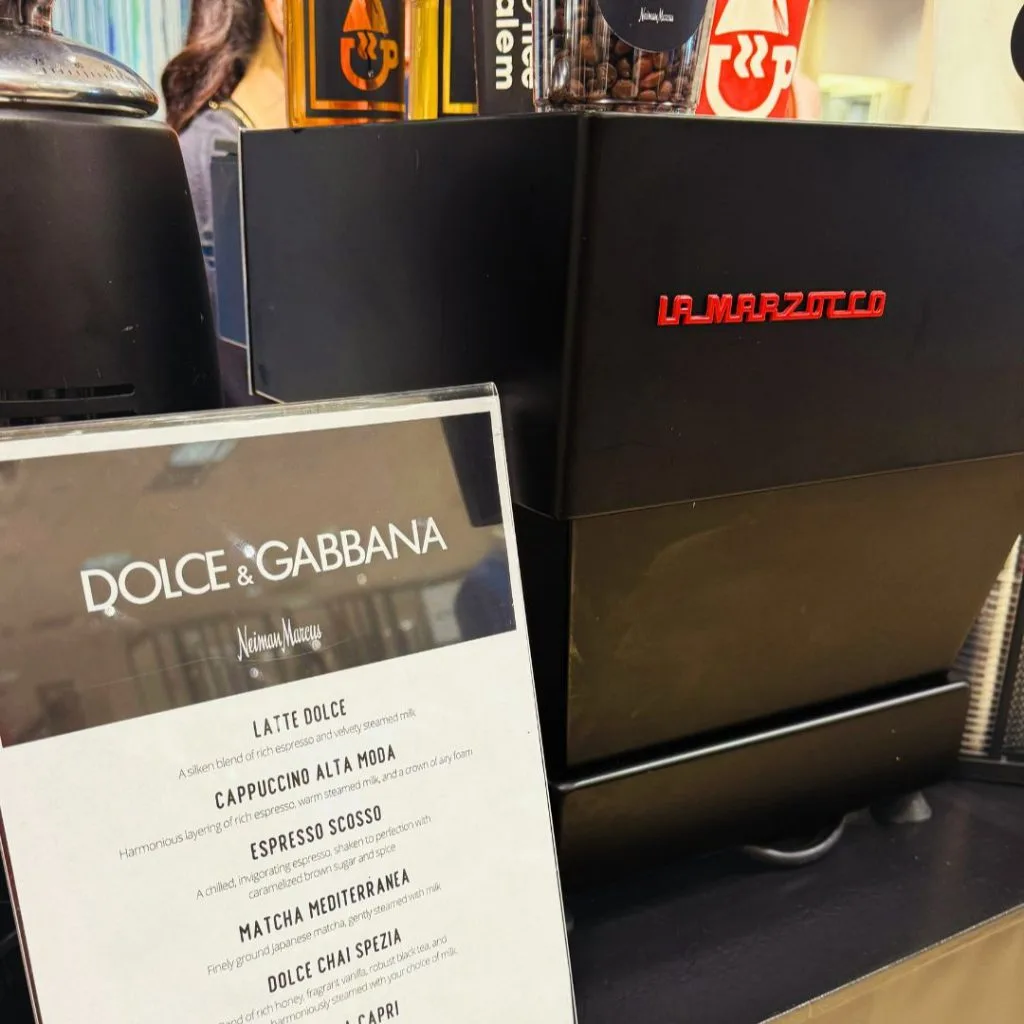Dolce & Gabbana coffee menu beside a La Marzocco espresso machine at Neiman Marcus.