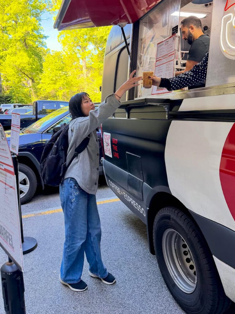 Coffee Malem barista handing a drink to a guest beside the coffee truck at Swarthmore College.